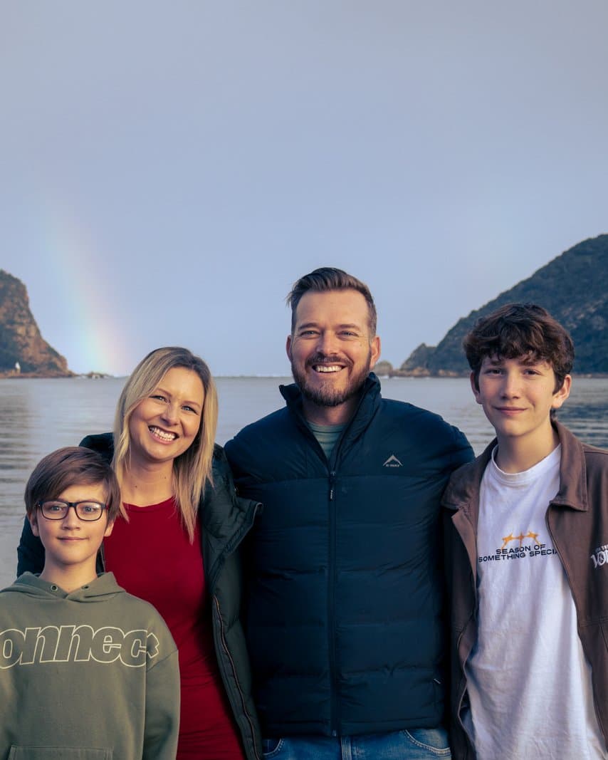 Colin and Nicky with their sons at the Knysna Heads, with a rainbow over the lagoon
